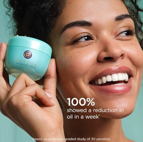 Smiling woman holding Tatcha The Water Cream.