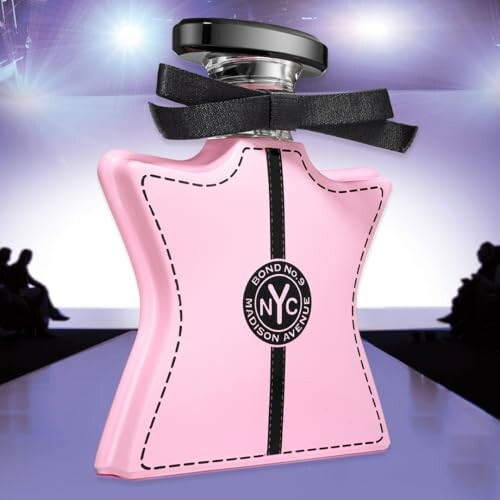 Pink star-shaped perfume bottle on a runway with audience silhouettes.