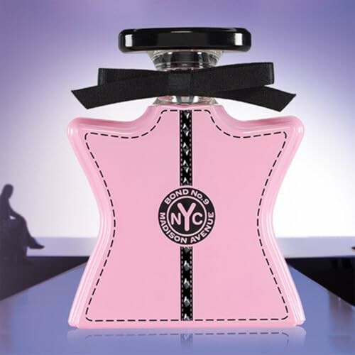 Pink star-shaped perfume bottle with black bow on runway background.