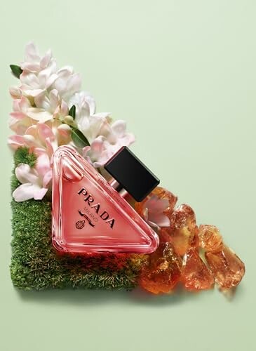 Prada Paradox perfume bottle with flowers and amber stones on green background