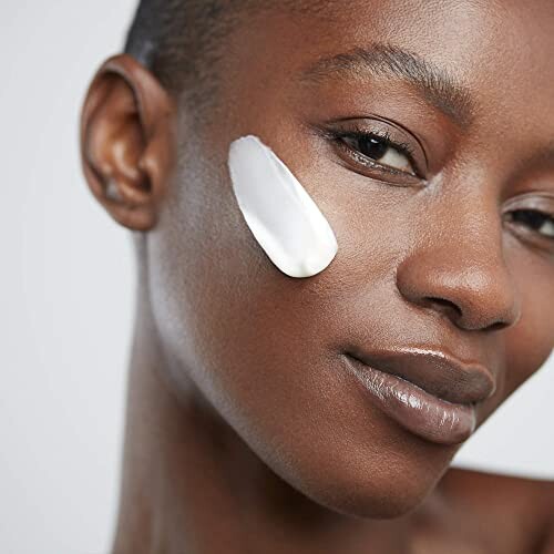 Close-up of a woman with skincare cream on her cheek.